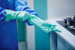 © Gabriel Trujillo/ADDICTIVE STOCK - Crop anonymous medical worker in surgical gown putting on rubber gloves before disinfecting endoscopy instruments in cleaning workstation