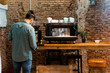 © Jake Jakab/ADDICTIVE STOCK - Back view male barista using portafilter and preparing coffee in modern coffeemaker while standing at counter in cafe