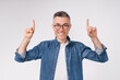 Cheerful caucasian mature man pointing at copy space isolated in white background