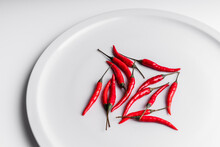 High Angle Composition Of Hot Red Chili Peppers Arranged On Ceramic Plate Against White Background