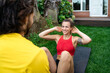 © Jordi Bataller/ADDICTIVE STOCK - Cheerful sportswoman doing abdominal crunches on mat with help of personal instructor in backyard during workout while looking at each other