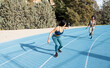 © Jose Carlos Cerdeno/ADDICTIVE STOCK - Fit multiracial female athletes passing baton while running along track at stadium during relay race