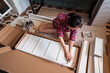 © Juan Alberto Ruiz/ADDICTIVE STOCK - From above ethnic Asian female sitting on floor with fluffy dog screwing screws in wooden board while assembling new furniture at home