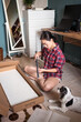 © Juan Alberto Ruiz/ADDICTIVE STOCK - Focused ethnic asian female sitting on floor with various details and fittings and assembling furniture in room with fluffy dog