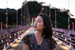 © Juan Alberto Ruiz/ADDICTIVE STOCK - Delighted Asian female standing on illuminated bridge in evening during summer vacation in Taiwan