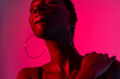 © Luis Manuel Munoz/ADDICTIVE STOCK - Self assured young African American female model in black top with closed eyes while standing against pink background in neon light