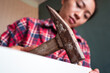 © Juan Alberto Ruiz/ADDICTIVE STOCK - From below focused ethnic female using hammer for nailing wooden dowels while assembling new furniture in apartment