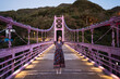 © Juan Alberto Ruiz/ADDICTIVE STOCK - Delighted Asian female standing with outstretched arms on illuminated bridge in evening during summer vacation in Taiwan