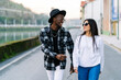 © Luis Manuel Munoz/ADDICTIVE STOCK - Young content multiracial partners in trendy clothes and sunglasses talking while looking at each other and strolling on city roadway