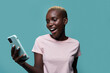 © Manuel Ruiz/ADDICTIVE STOCK - Expressive beautiful African American female with short hair and bright manicure browsing on smartphone against blue background