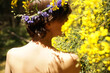© Marianna Jaszczuk/ADDICTIVE STOCK - Back view of calm adult naked female with floral wreath on head resting in garden near blooming tree with yellow flowers on sunny day