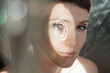 © Marianna Jaszczuk/ADDICTIVE STOCK - Through glass of peaceful adult lady with short hair looking at camera on sunny day