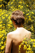 © Marianna Jaszczuk/ADDICTIVE STOCK - Back view of unrecognizable calm adult naked female resting in garden near blooming tree with yellow flowers on sunny day