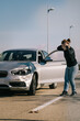 © Older Garcia/ADDICTIVE STOCK - Full body of young stressed female driver in casual clothes touching head while standing on asphalt road and looking at damaged bonnet with opened mouth after accident