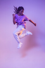 Full Body Of Dynamic African American Teen Dancer Leaping Up While Performing Dance Movement In Bright Studio