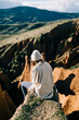 © Nacho Zaitsev/ADDICTIVE STOCK - Back view of unrecognizable female tourist contemplating green mountains while resting on gorge in Spain