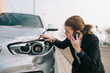 © Older Garcia/ADDICTIVE STOCK - Upset young female driver in casual outfit having phone conversation on road and inspecting damages on modern car after crash