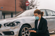 © Older Garcia/ADDICTIVE STOCK - Side view of unrecognizable female insurance agent in formal outfit and protective mask writing protocol near damaged car parked on street after accident