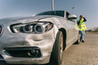 © Older Garcia/ADDICTIVE STOCK - Unhappy young female driver in yellow road safety vest having phone conversation and checking damages on modern car parked on pavement after crash