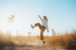 © Miguel Palomo/ADDICTIVE STOCK - Side view of active young lady in trendy outfit dancing in dry fiends against cloudless blue sky in countryside