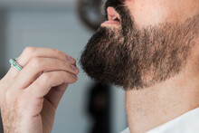 Side View Closeup Of Crop Anonymous Hipster Male In Ring Touching Beard In Hairdressing Salon In Daytime