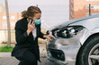 © Older Garcia/ADDICTIVE STOCK - Unrecognizable young female driver in casual clothes and face mask talking on mobile phone while standing near modern damaged car after accident on city road