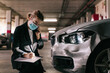 © Older Garcia/ADDICTIVE STOCK - Unrecognizable concentrated female insurance officer in formal suit and protective mask talking on mobile phone while inspecting car damages and filling out claim after accident