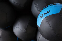 Set Of Black Medicine Balls For Functional Training Stacked In Rows Near Wall In Modern Sports Club
