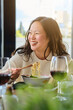 © Philippe Degroote/ADDICTIVE STOCK - Delighted young Asian female enjoying delicious traditional ramen while sitting at table with glass of wine during dinner in restaurant