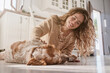 © Philippe Degroote/ADDICTIVE STOCK - Smiling female owner sitting on floor at home and stroking fluffy Setter dog
