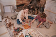 © Philippe Degroote/ADDICTIVE STOCK - From above of female artist and teenager sitting on floor with dog and creating painting together while enjoying weekend in house near fireplace