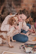 © Philippe Degroote/ADDICTIVE STOCK - Content female painter hugging adorable Setter dog while creating artwork with paints and brush on floor in cozy house
