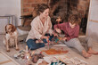 © Philippe Degroote/ADDICTIVE STOCK - Female artist and teenager sitting on floor with dog and creating painting together while enjoying weekend in house near fireplace