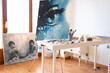 © The Trio Studio/ADDICTIVE STOCK - Art studio interior with collection of painted pictures and paint brushes in glass on table in daylight