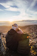 © Ruben Soto/ADDICTIVE STOCK - Back view of unrecognizable man embracing girlfriend in outerwear while admiring dawn from mountain under cloudy sky in sunshine
