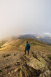 © Ruben Soto/ADDICTIVE STOCK - From above back view of anonymous male trekker with rucksack standing on pathway against mount on misty day