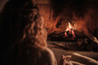 © Philippe Degroote/ADDICTIVE STOCK - Back view high angle of female sitting with notebook on carpet and looking at fire burning in fireplace in cozy house