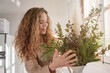 © Philippe Degroote/ADDICTIVE STOCK - Gentle female standing at table with bunch of fresh green plants in vase at home
