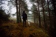 © Ruben Soto/ADDICTIVE STOCK - Back view of anonymous male walking along path in woods with dog on foggy day