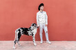 © Sergio Victor Vega/ADDICTIVE STOCK - Male owner standing with big Harlequin Great Dane dog during stroll in city and looking away