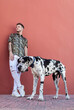 © Sergio Victor Vega/ADDICTIVE STOCK - Male owner standing with big Harlequin Great Dane dog during stroll in city and looking away