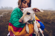 © Ruben Soto/ADDICTIVE STOCK - Side view of loving female owner kissing adorable white dog during stroll in nature on foggy day