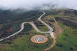 © Ruben Soto/ADDICTIVE STOCK - Spectacular drone view of curved serpent road near round concrete helipad on grassy rural valley on summer day running through green hills in highlands