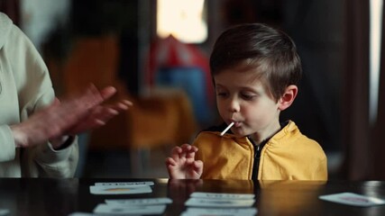 Sticker - little boy learns words from cards under the ABA therapy program at home at the table