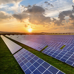 blue solar photo voltaic panels producing renewable clean energy on rural landscape and setting sun 