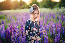 Beautiful Woman With Purple Flowers In A Lupine Spring Field. Beauty Outdoor Portrait