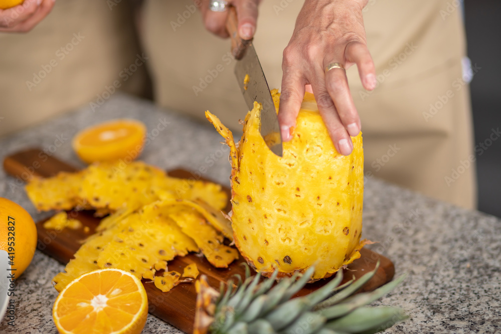 acercamiento de la mano de una mujer cortando una piña en la cocina ...