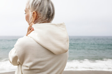 Wall Mural - Senior woman in hoodie relaxing at the beach