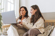 Mother middle aged woman and daughter teenager using laptop together in the light interior