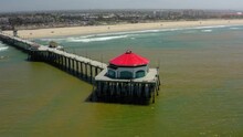 Aerial Panning: Pier At Beach In Coastal City On Sunny Day
